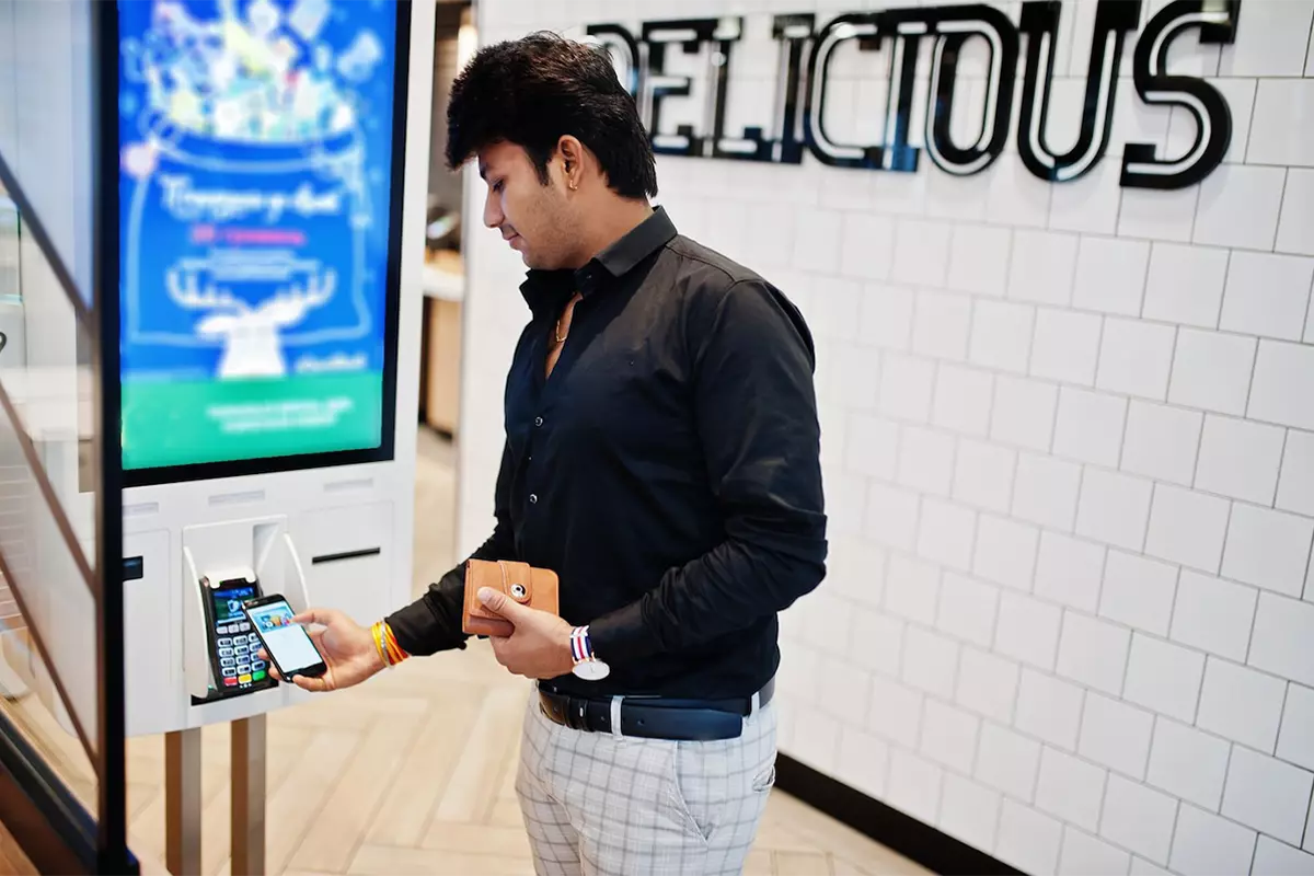 indian man customer store place orders pay by contactless credit card mobile phone through self pay floor kiosk fast food payment terminal pay pass 1200x800 1