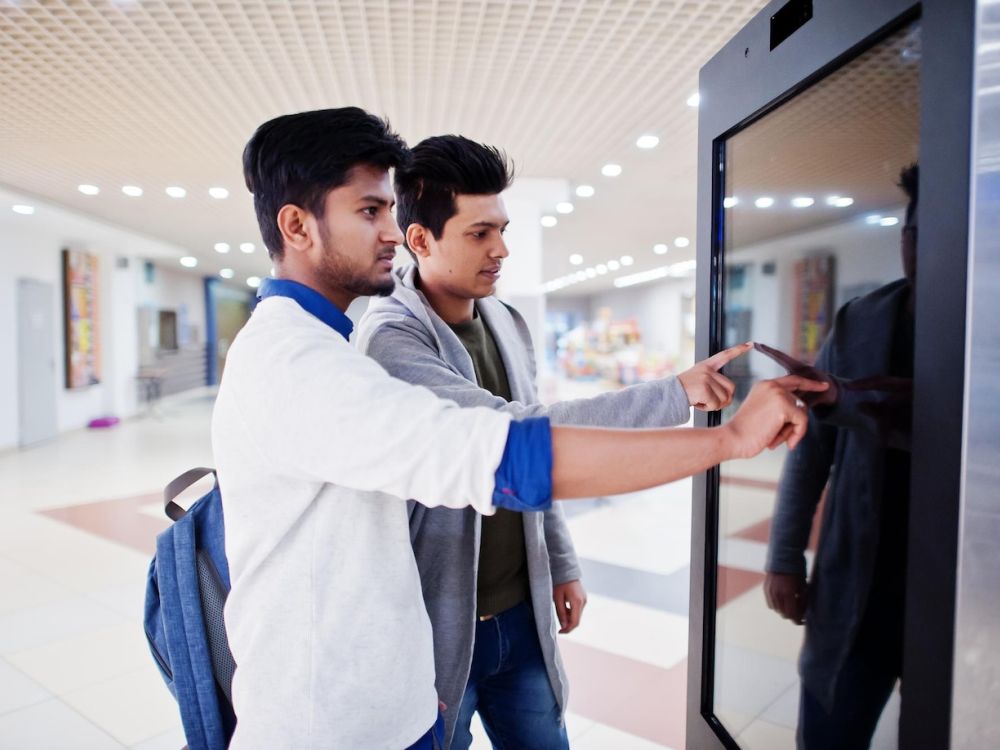 two guys touching screen kiosk at malll